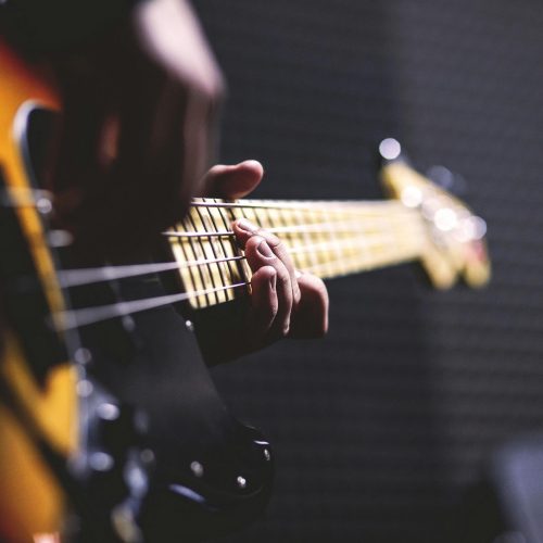 Close-up of a musician strumming an electric bass guitar with focus on fingers.